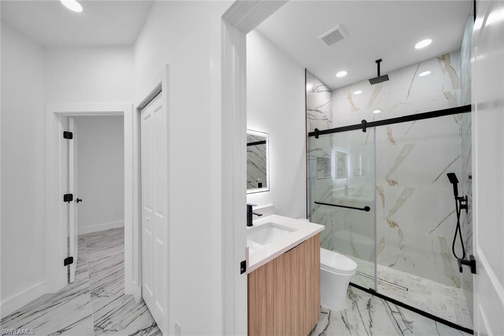 Modern bathroom featuring a glass-enclosed shower with black-finish fixtures, a rain showerhead, and a handheld spray