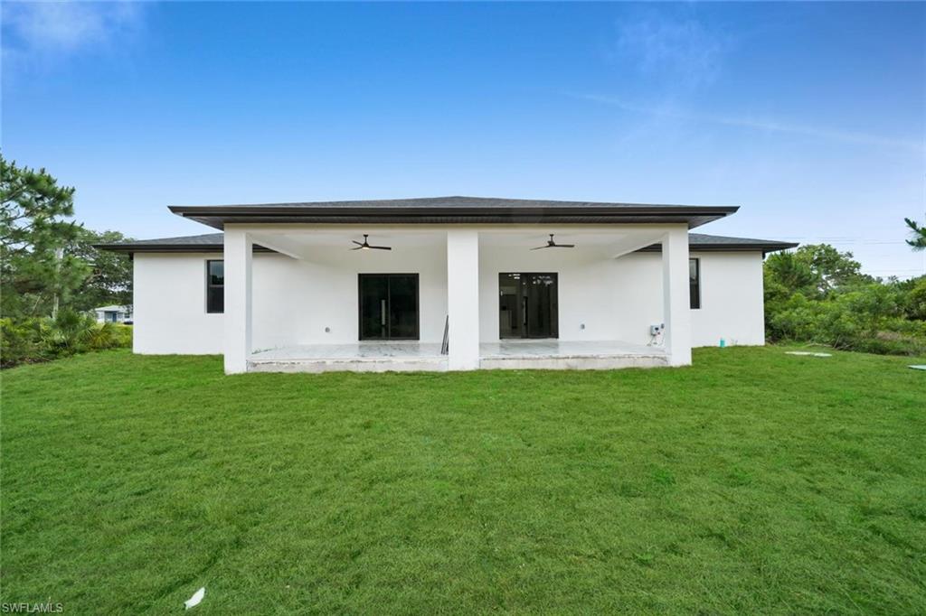 Spacious rear patio featuring a covered design, dual ceiling fans, and sliding glass doors