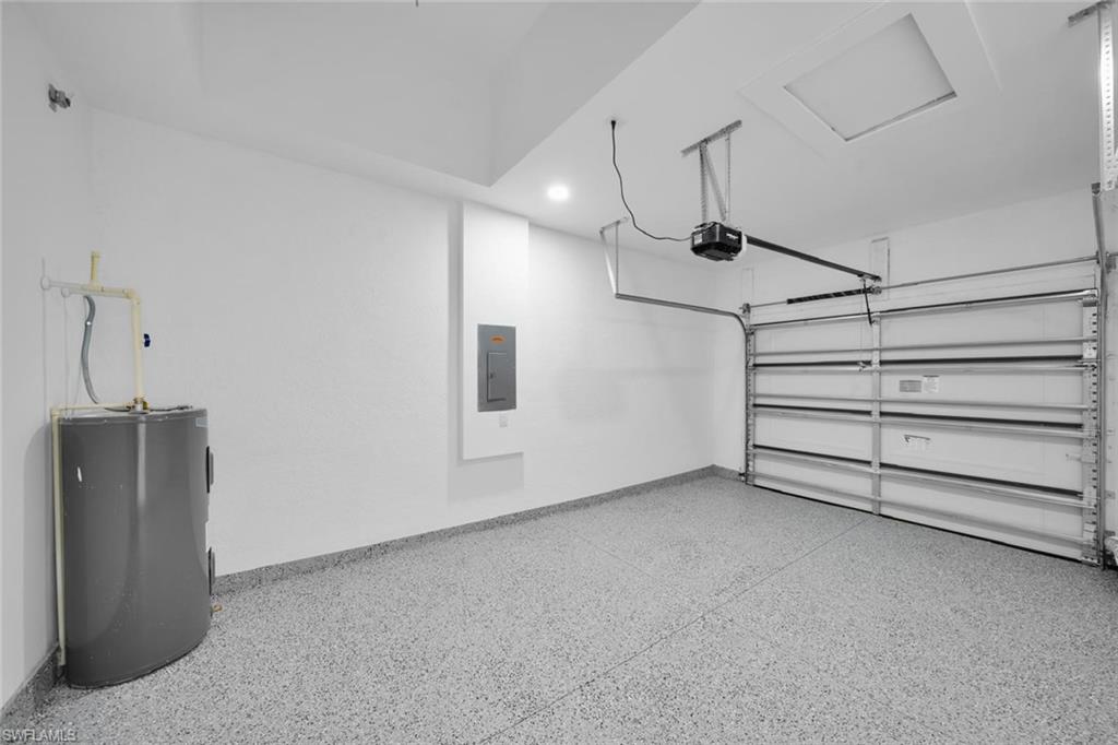 Spacious garage featuring a finished epoxy floor, automatic garage door opener, and a panel for electrical access