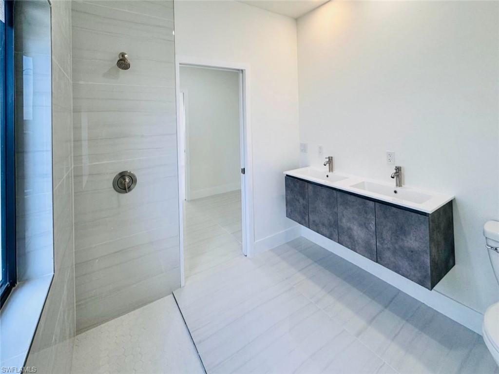 Contemporary bathroom featuring a floating dual vanity with integrated sinks, a walk-in shower with large format tile, and coordinating floor tiling