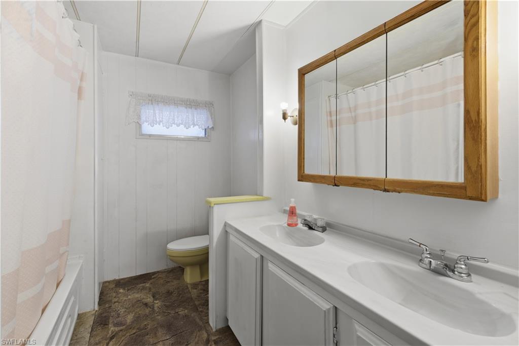 Dual vanity with integrated sinks, wood-finish medicine cabinet, and wall-mounted sconce lighting