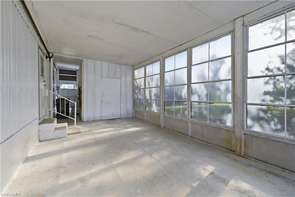 Enclosed porch featuring a row of large window panes and concrete flooring