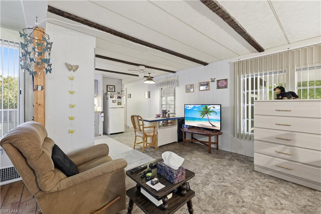 Spacious living area featuring vinyl flooring and visible ceiling beams