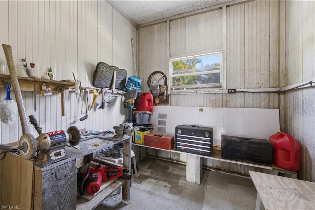 Utility room with a built-in workbench, wall-mounted shelving, and a horizontal window