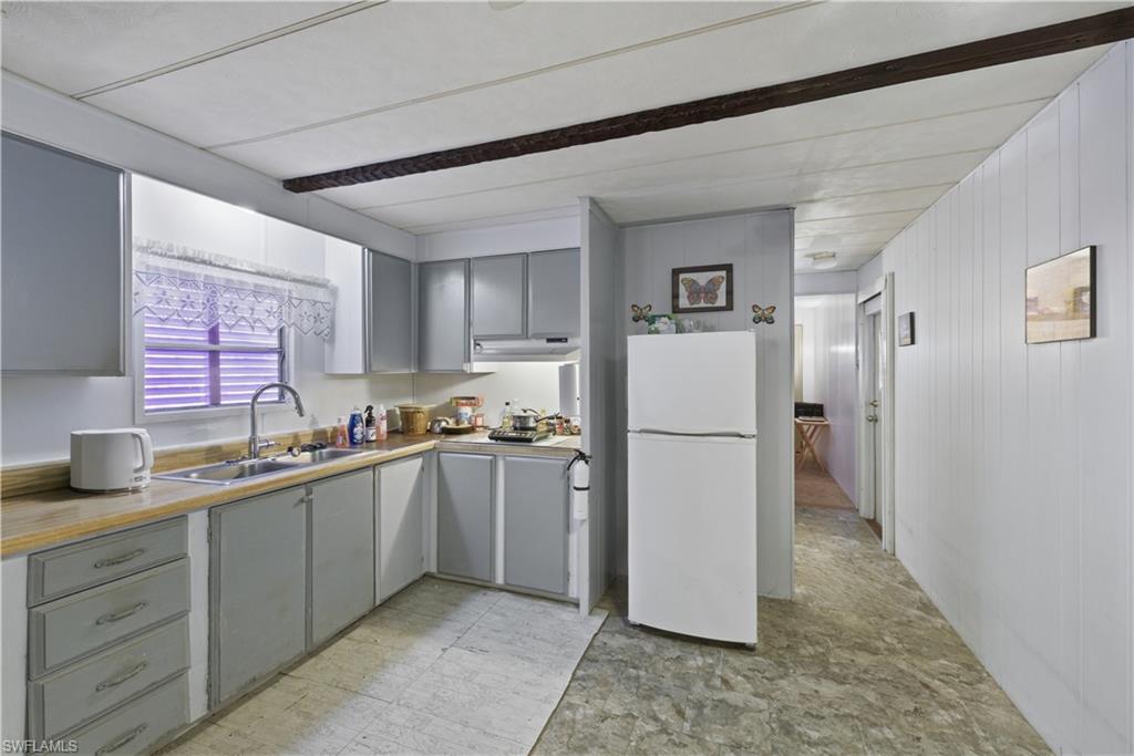 Kitchen featuring light gray cabinetry, wood-finish countertops, and a double-basin sink with a gooseneck faucet