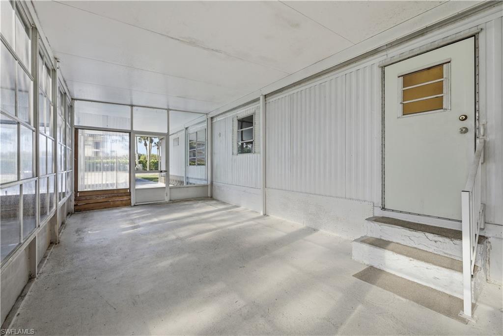 Screened lanai featuring concrete flooring, a white metal frame, and an entry door with a privacy window