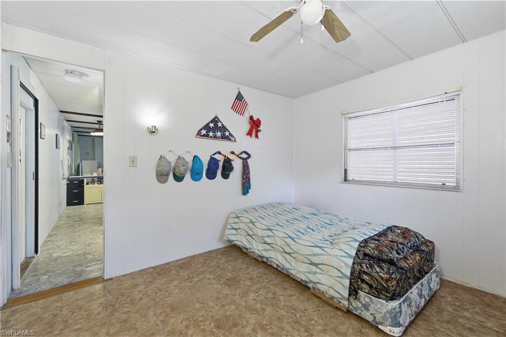 Room featuring wood-finish flooring, a ceiling fan, and a window with blinds