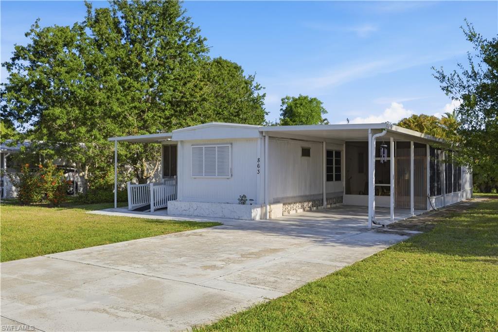 Single-story residence featuring a white vertical siding exterior, a covered carport, and an extended screened porch