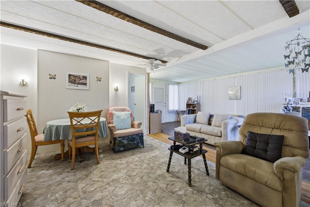 Open-concept living area featuring a wood-beam ceiling, textured wall paneling, and resilient flooring