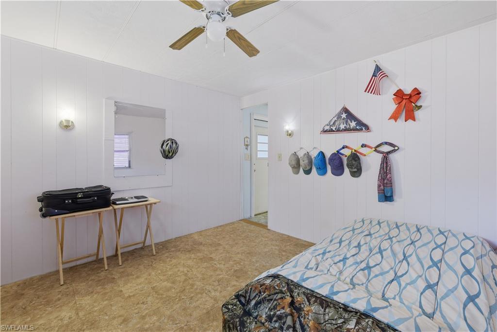 Bedroom featuring panel walls, wall-mounted light fixtures, a ceiling fan, and patterned floor covering