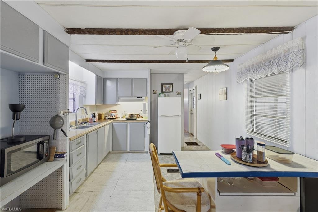 Kitchen featuring gray cabinetry, light countertops, and white appliances