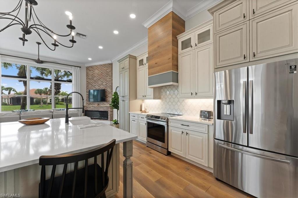 Kitchen featuring appliances with stainless steel finishes, ornamental molding, light countertops, a chandelier, and a sink