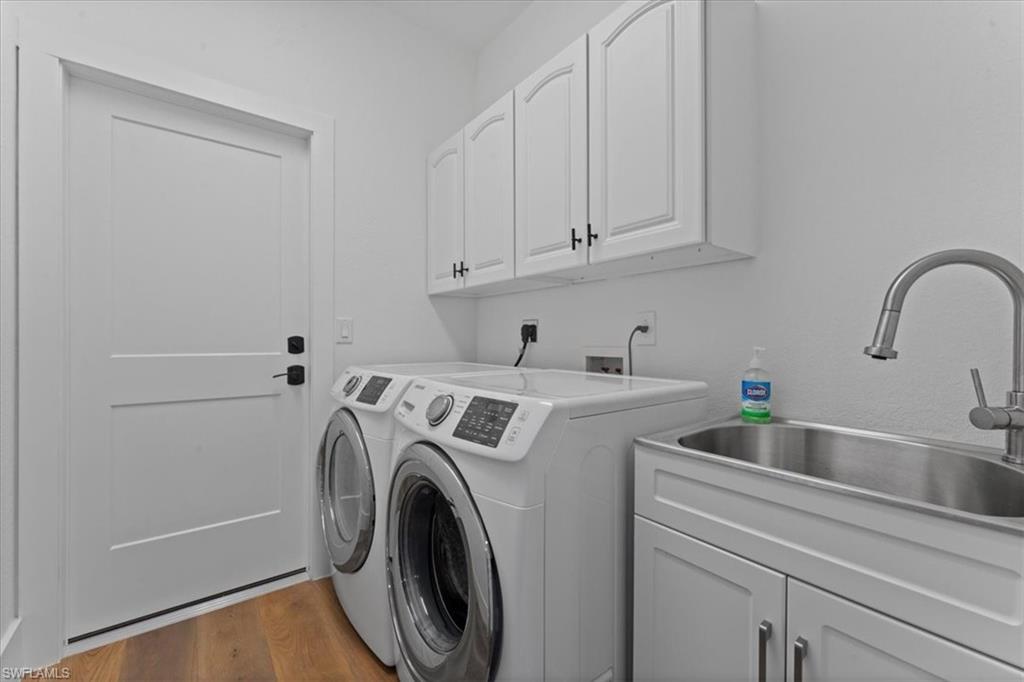 Washroom featuring cabinet space, washing machine and clothes dryer, and dark wood-style flooring