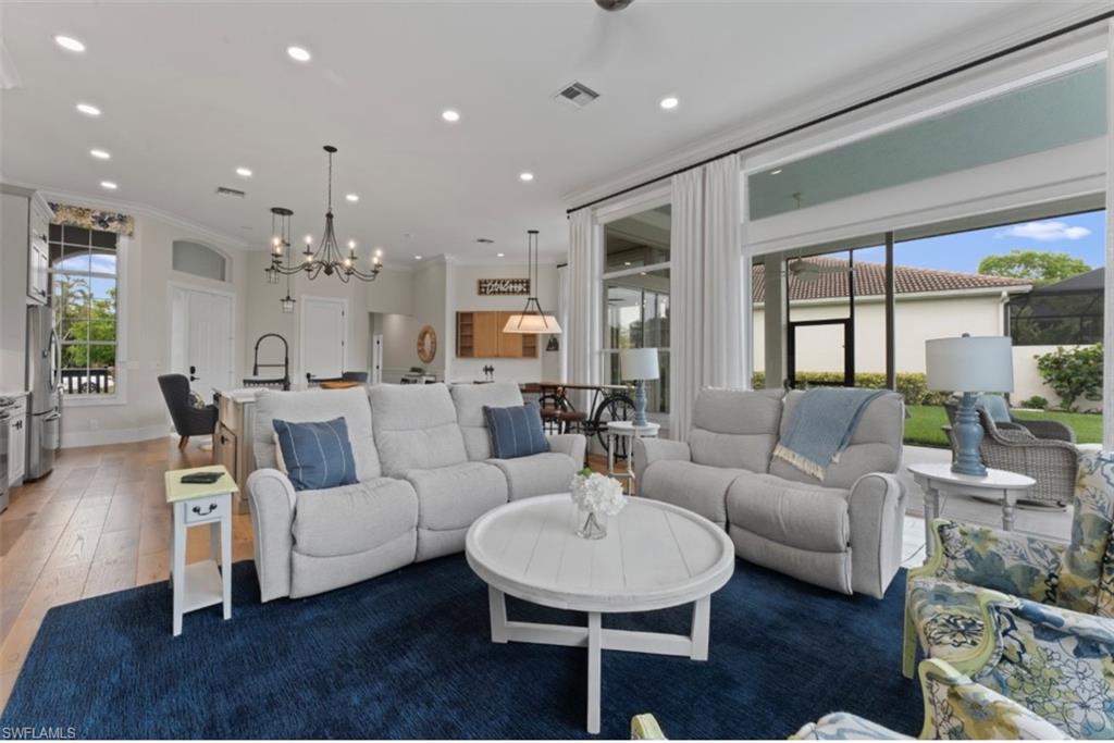 Living room with light wood-style floors, recessed lighting, a chandelier, and ornamental molding