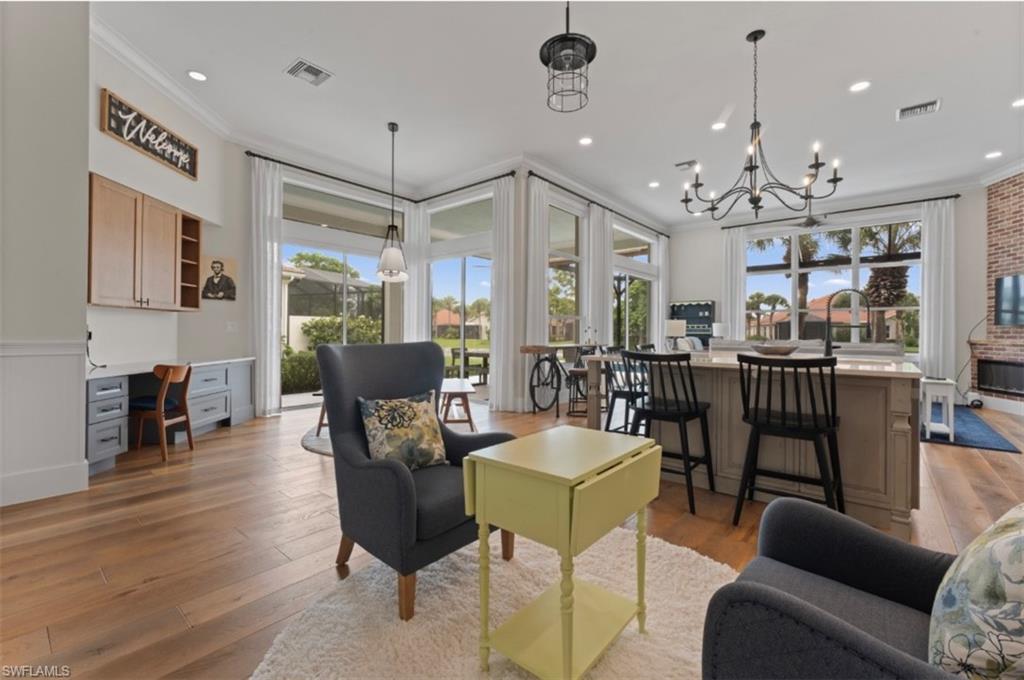Living area featuring crown molding, light wood-style floors, a chandelier, recessed lighting, and a wainscoted wall