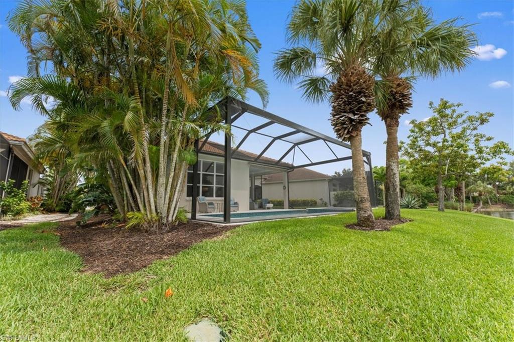 View of grassy yard with an outdoor pool and glass enclosure