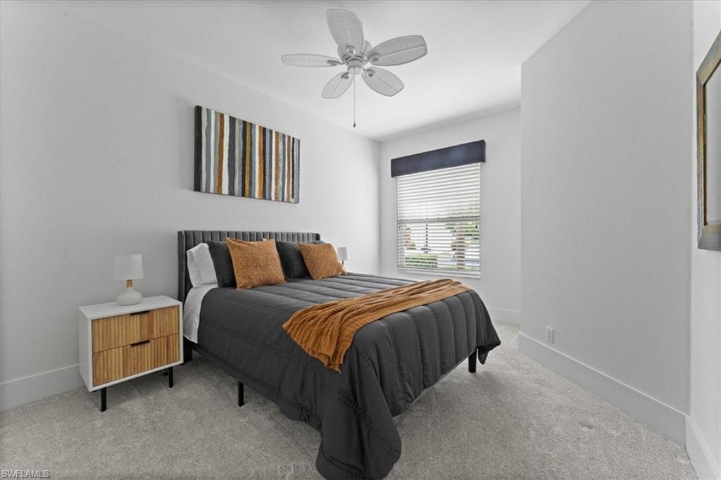 Bedroom with light colored carpet, baseboards, and a ceiling fan