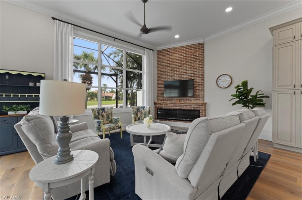 Living area featuring a fireplace, light wood finished floors, recessed lighting, ornamental molding, and ceiling fan