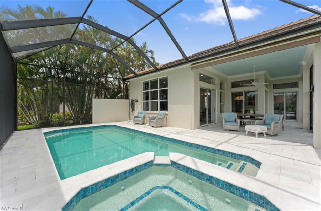 View of swimming pool with a patio, ceiling fan, a pool with connected hot tub, and glass enclosure