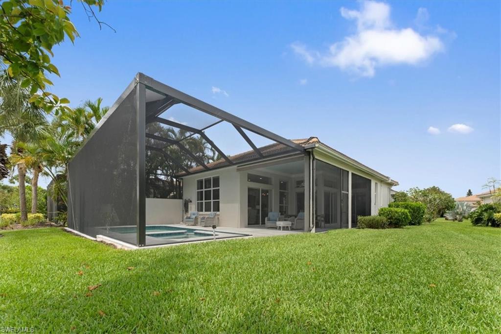 Back of property featuring a lawn, a lanai, stucco siding, an outdoor pool, and a patio area
