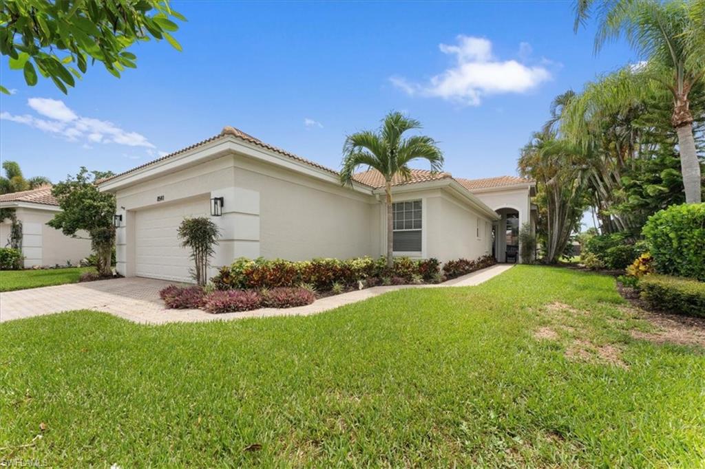View of front of home with stucco siding, a tile roof, a front yard, and driveway