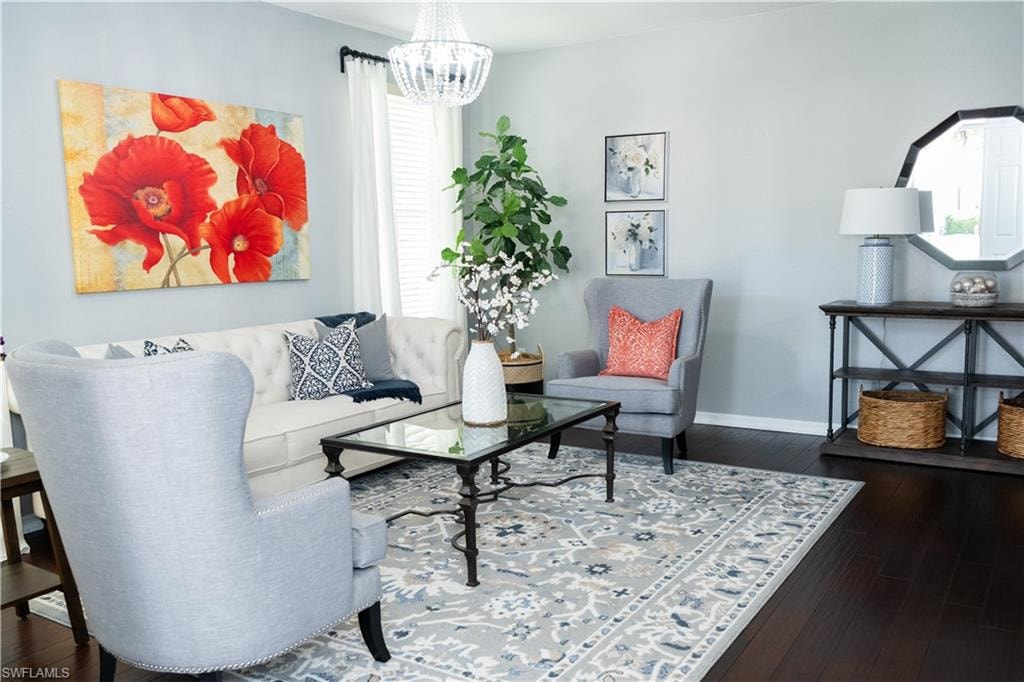 Spacious living area featuring dark wood-finish flooring, a contemporary chandelier, and light-toned walls
