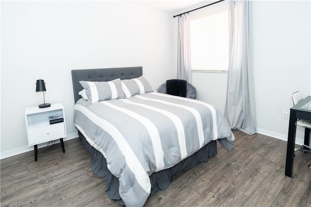 Wood-finish flooring throughout, white walls, and a window with blinds and drapes