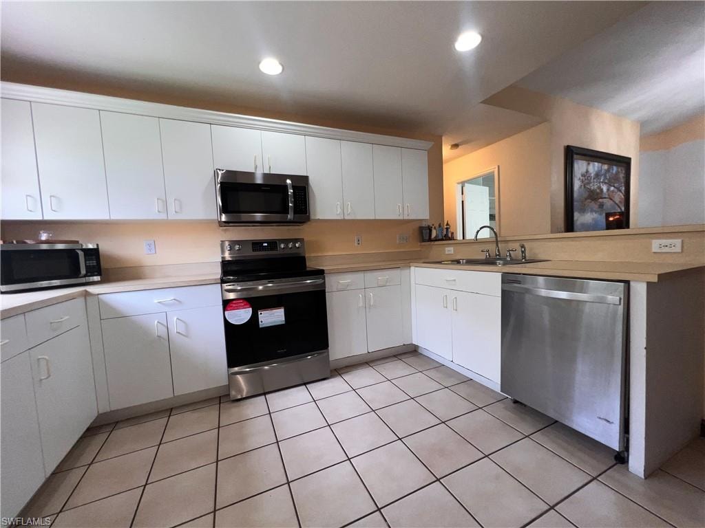 Kitchen featuring white cabinetry, light-toned countertops, and stainless steel appliances including a range, microwave, and dishwasher