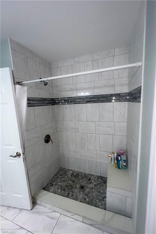 Walk-in shower featuring light-toned rectangular wall tiles, a decorative glass tile accent band, a pebble-stone shower floor, a built-in shower bench, and a bronze-finish shower fixture