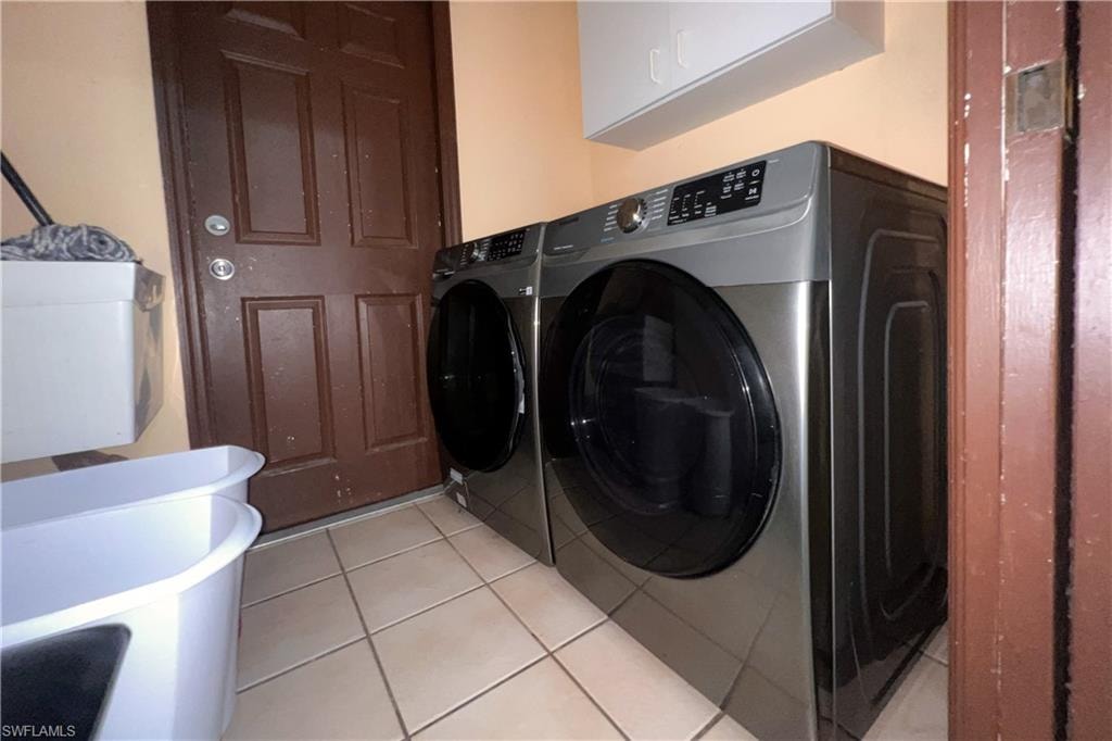 Utility area featuring ceramic tile flooring, a dark paneled door, and overhead white cabinetry