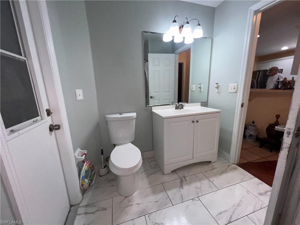 Bathroom featuring a white single-sink vanity with cabinet storage, a wall-mounted mirror, and a three-bulb light fixture