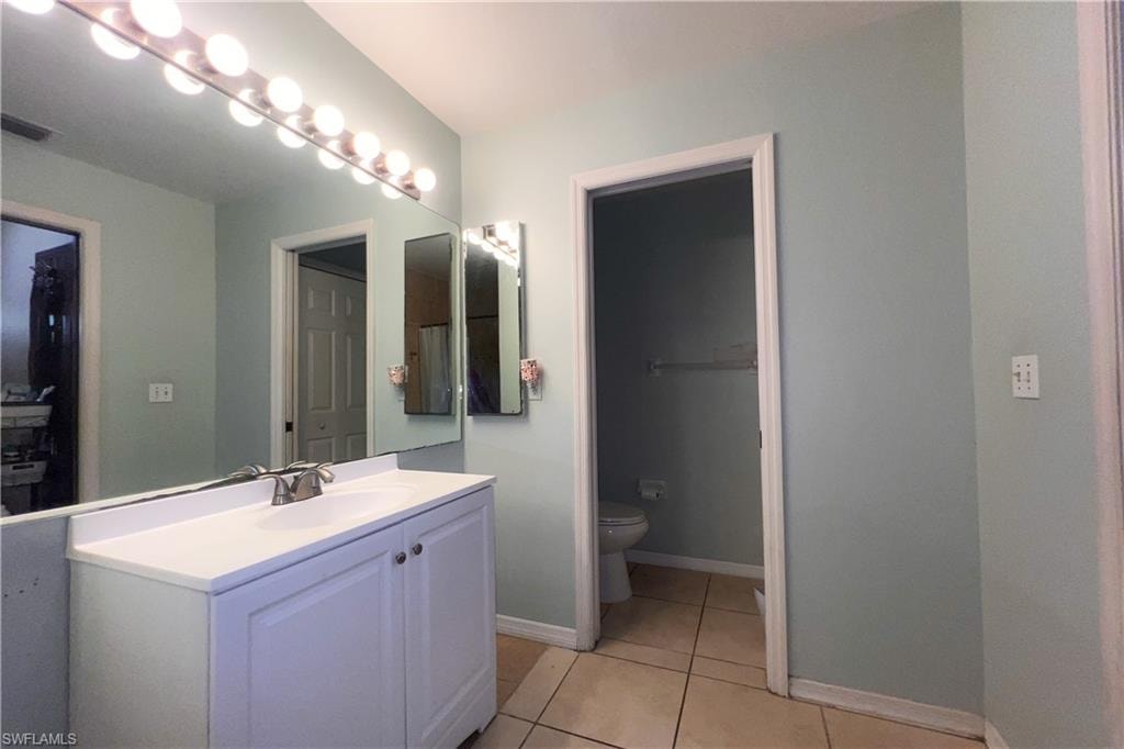 Bathroom featuring a vanity with a white countertop and base cabinetry, a large wall-mounted mirror, and tile flooring