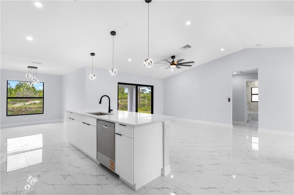 Open-concept interior featuring large format marble-look tile flooring, a central kitchen island with a built-in stainless steel dishwasher, modern pendant lighting, a black ceiling fan, and recessed lighting