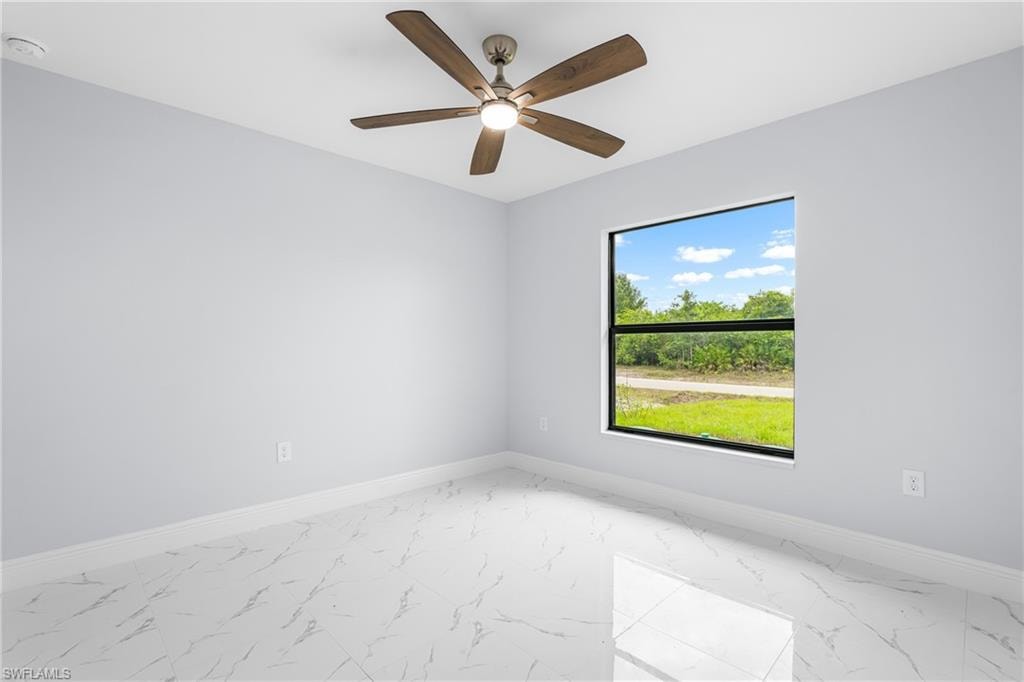 Bright room featuring a large window, a ceiling fan with integrated lighting, and white baseboards