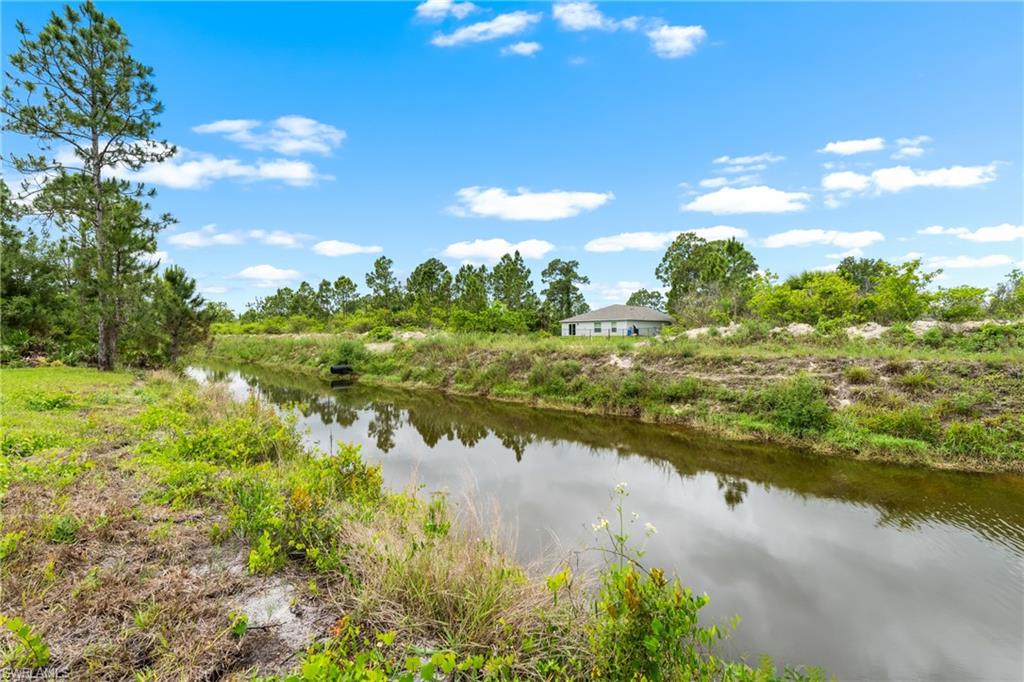 Waterfront property featuring a canal, natural landscaping, and mature trees