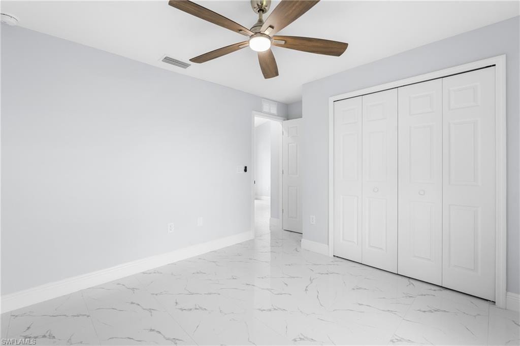 Spacious room featuring light-colored walls, white baseboards, and marble-look tile flooring