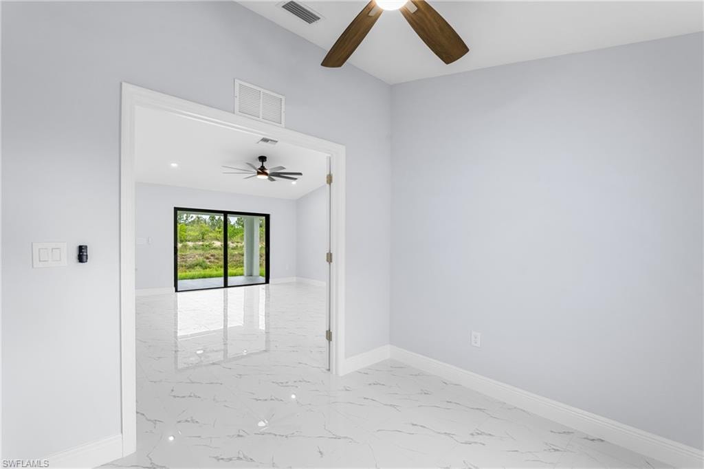 Spacious interior room featuring light-toned wall paint and white baseboards