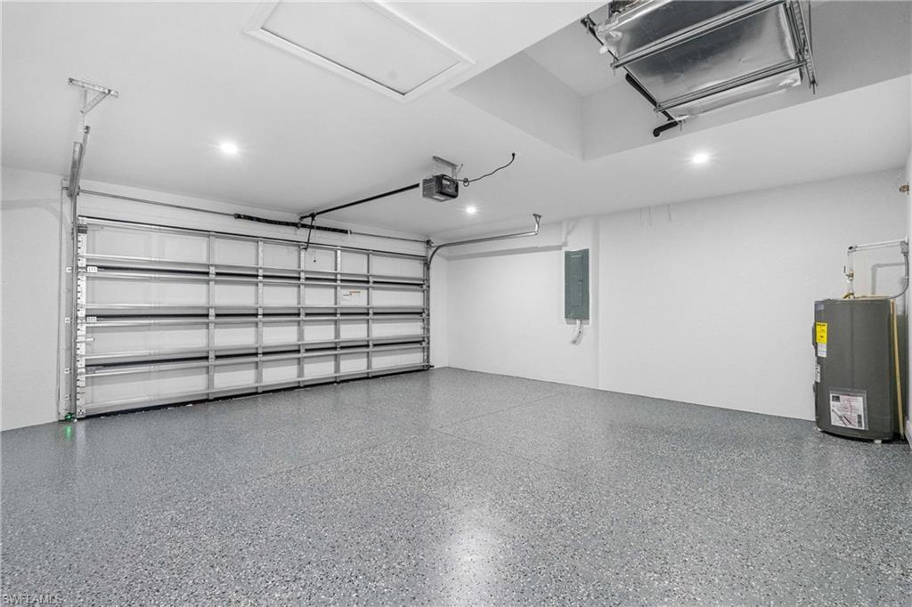 Spacious garage featuring a durable epoxy-coated floor, bright recessed lighting, and a paneled garage door with an automatic opener
