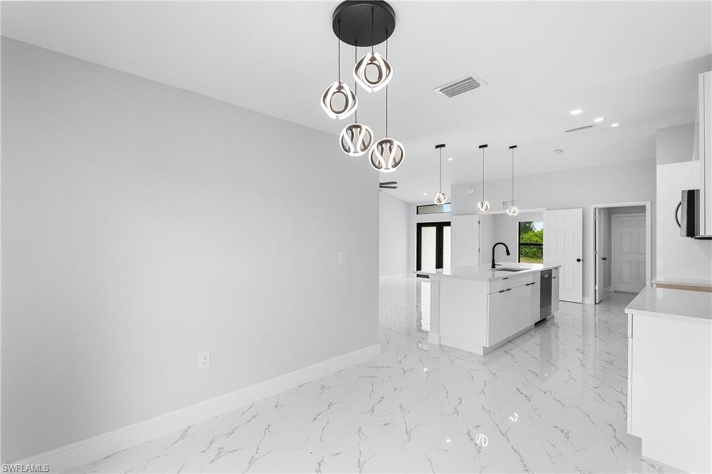 Open-concept kitchen and living area featuring a modern chandelier, white shaker cabinetry, an island with a black gooseneck faucet, stainless steel appliances, and large format white tile flooring