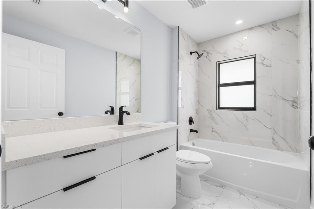 Modern bathroom featuring a white vanity with a light-toned countertop, a black single-handle faucet, and a large wall-mounted mirror