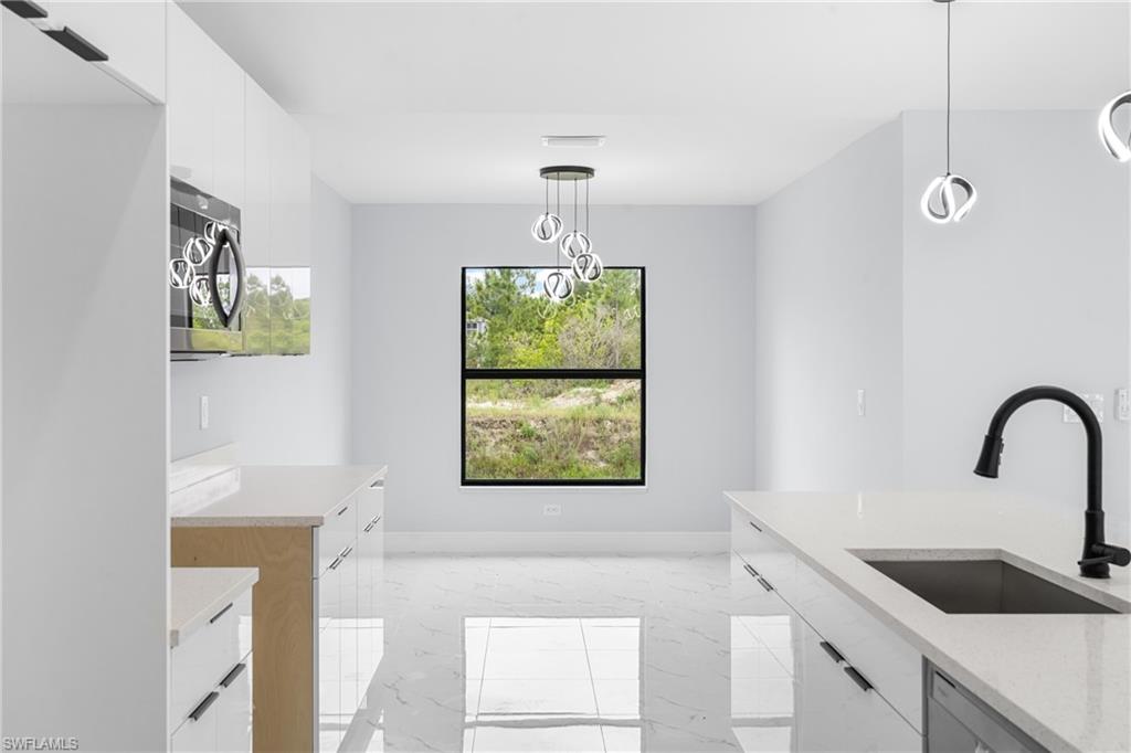 Open-concept kitchen featuring white cabinetry, light-toned countertops, and contemporary pendant lighting