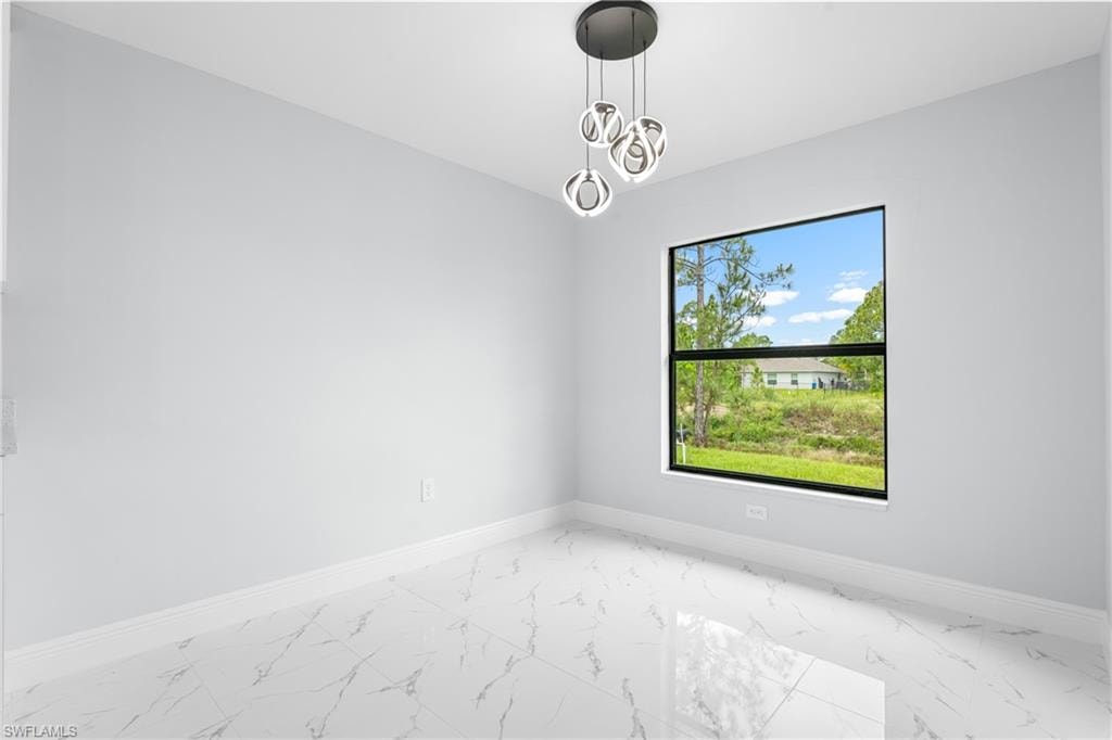 Bright interior space featuring large format marble-look tile flooring, white baseboards, and light gray walls