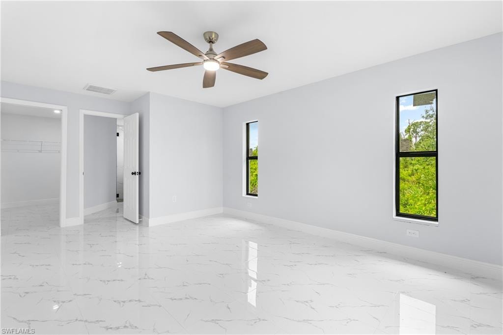 Spacious room featuring white tile flooring, light gray walls, and two vertical windows