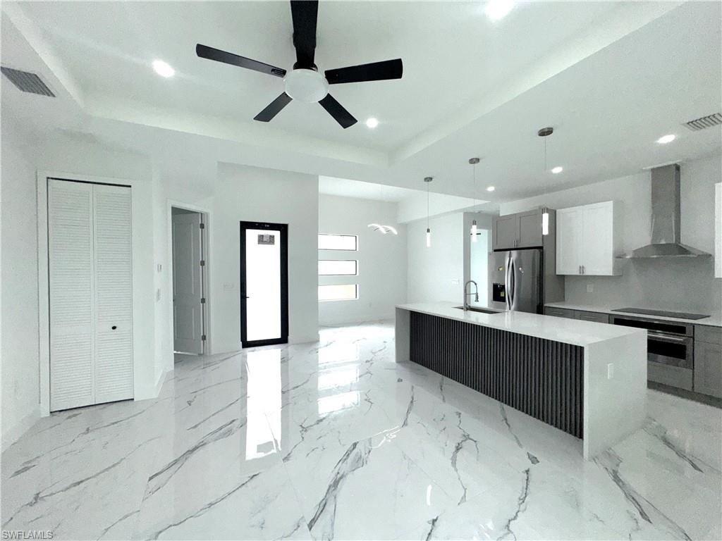 Open-concept kitchen and living area featuring high ceilings, recessed lighting, and large format white tile flooring with gray veining