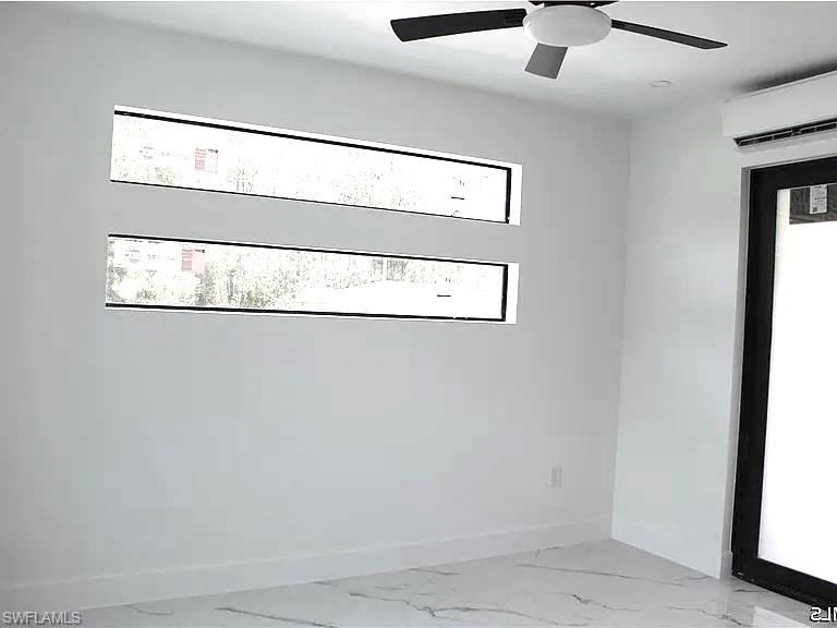 White-walled interior with a ceiling fan, two horizontal windows, and a black-framed door