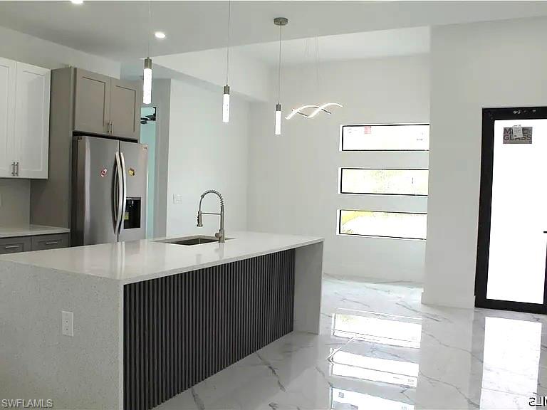 Kitchen island featuring a waterfall countertop and fluted paneling