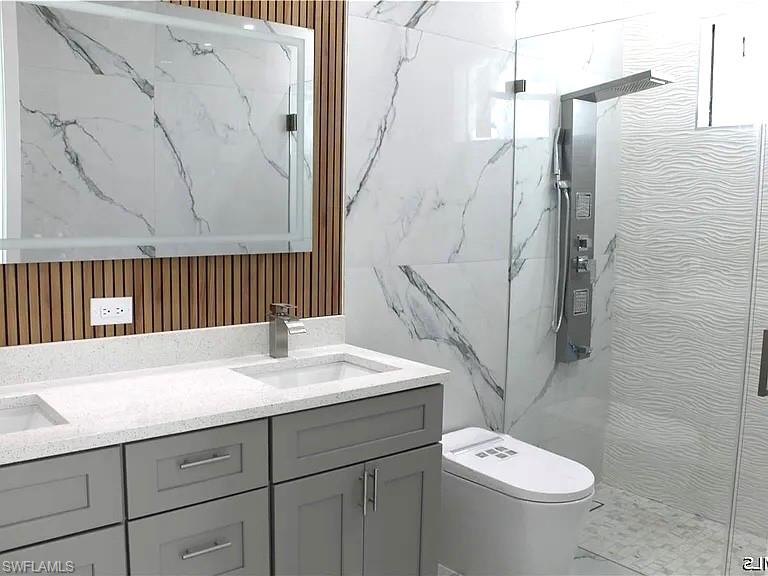 Modern bathroom featuring a dual vanity with gray cabinetry, white countertops, and integrated sinks