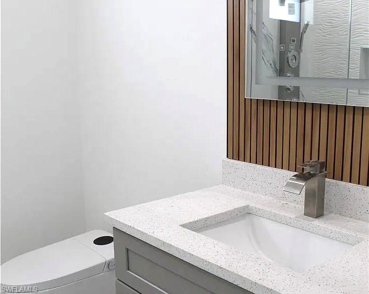 Contemporary vanity featuring a light gray cabinet, a white speckled countertop, and an undermount sink with a brushed nickel waterfall faucet