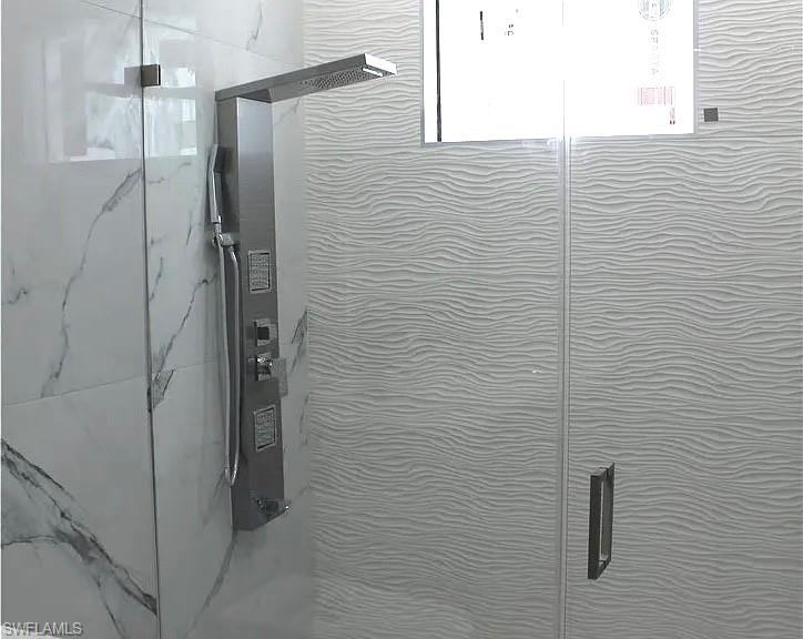 Shower enclosure featuring a multi-function shower panel with an overhead rain shower and handheld sprayer