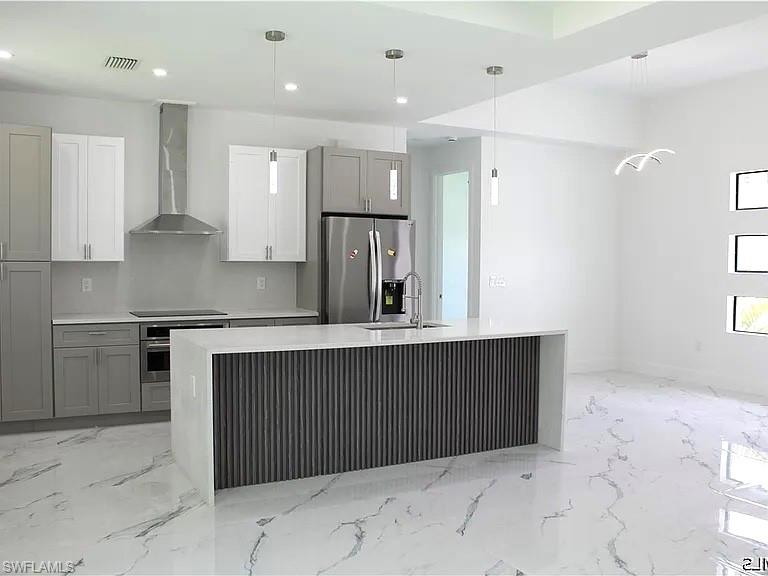 Open-concept kitchen featuring an island with a waterfall countertop, integrated sink, and modern pendant lighting